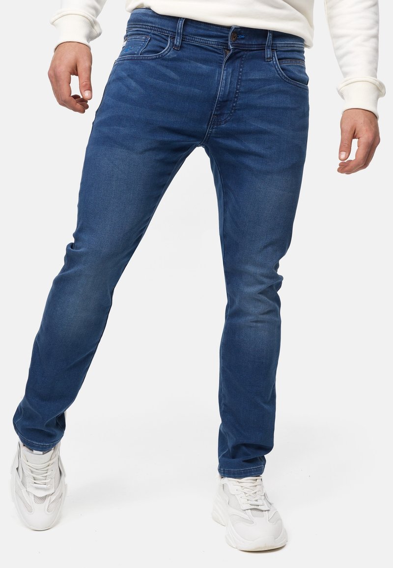 Jeans in denim di tonalità blu media, caratterizzati da un design slim-fit, classica struttura a cinque tasche e sottili sfumature sulla parte anteriore.