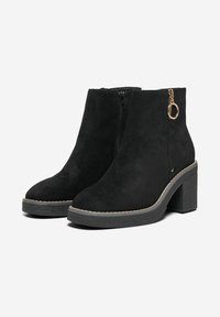 Black suede ankle boots with a rounded toe, side zipper, gold hardware accent, and a textured black block heel.