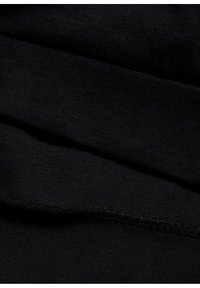 Tessuto nero con una morbida texture, che mostra una finitura liscia e cuciture fini lungo i bordi, piegato per evidenziare i dettagli a strati.