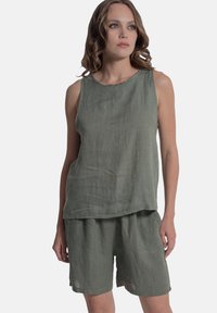 Completo in lino a due pezzi di un verde tenue, con top senza maniche dal collo curvo e pantaloni shorts morbidi con vita elastica.