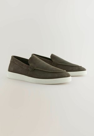 Slip-On-Schuhe aus dunkelgrünem, strukturiertem Material mit einer weißen Gummisohle und dezenten Nähten, die ein schlankes, minimalistisches Design aufweisen.