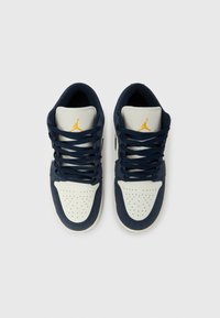 Παπούτσια σνίκερς σε ναυτικό μπλε και λευκό με διατρημένα καλύμματα δακτύλων, χρυσές λεπτομέρειες και επίπεδα κορδόνια. Διαθέτουν υλικά υφασμάτινα και δερμάτινα.