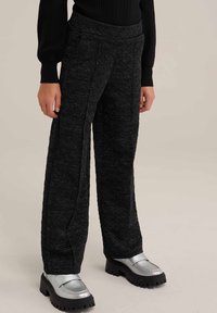 Zwarte gestructureerde broek met wijde pijpen en een zachte afwerking, voorzien van zijzakken en een elastische tailleband, gecombineerd met zilveren plateau schoenen.
