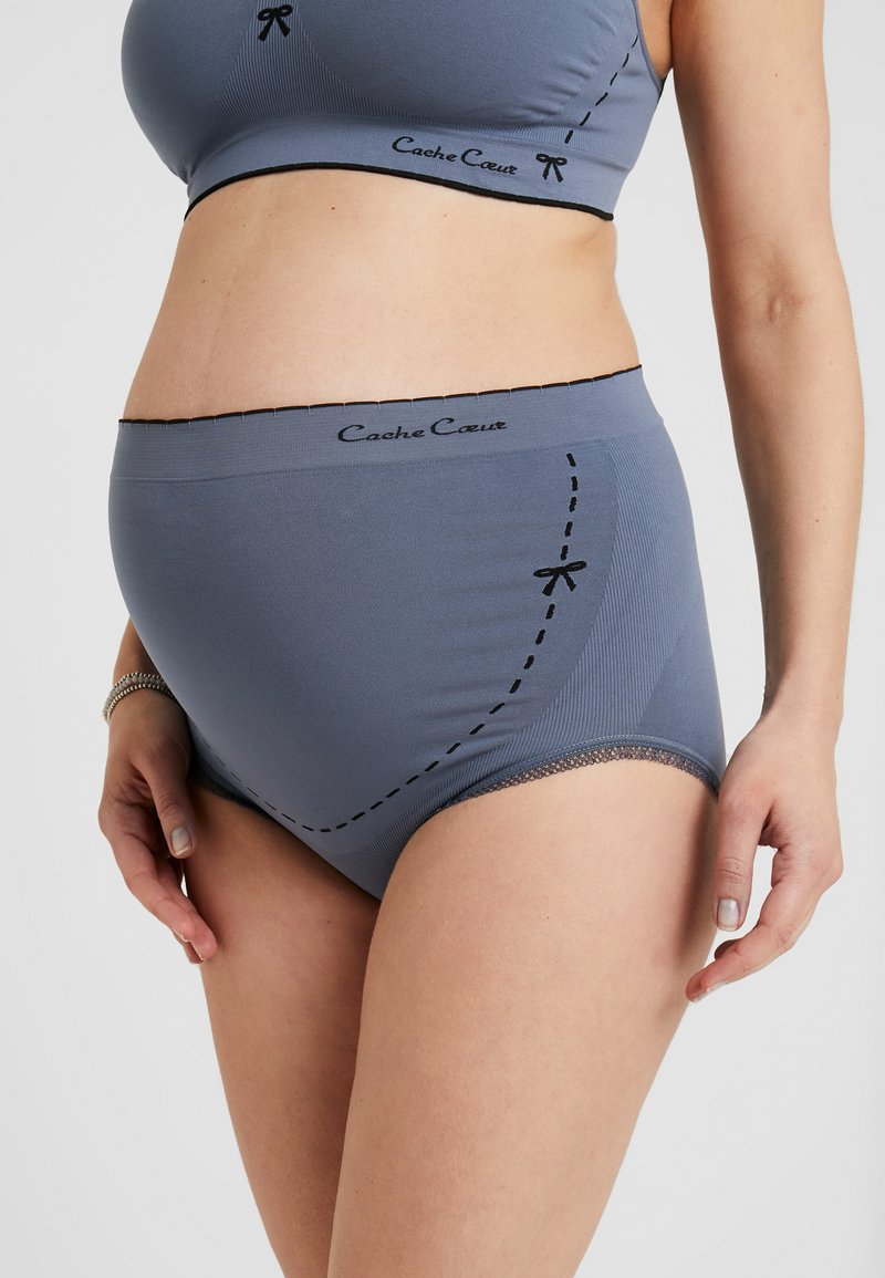 Culotte de maternité grise à côtes avec détails de couture noire et garniture en dentelle, offrant un confort optimal et une marque sur la ceinture.