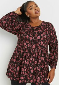 Tunic nera floreale con maniche a campana, chiusura con bottoni e design a strati con fiori rosa. Tessuto morbido con un aspetto strutturato.