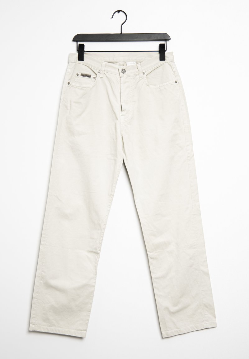 Světlé béžové kalhoty širokého střihu vyrobené z bavlny, s dvěma předními kapsami, kovovým uzávěrem a textilní etiketou na pásu.