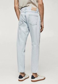 Světlé modré džíny s uvolněným střihem, pěti kapsami a koženou nášivkou na zadním pásu. Hladká textura s mírným vyblednutím.