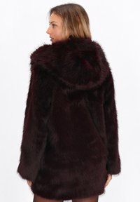 Burgundy faux fur coat with a hood, featuring a soft, fluffy texture and long sleeves, cut to mid-thigh with a straight silhouette.