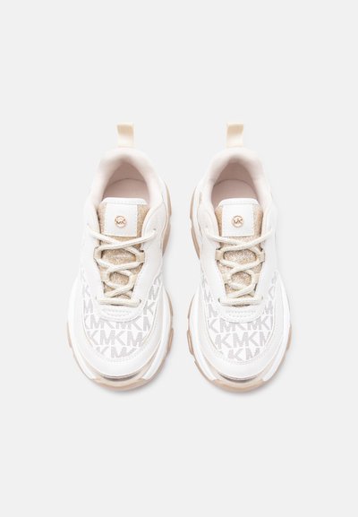 Λευκά και μπεζ αθλητικά παπούτσια με μοτίβο μονόγραμμου MK, γυαλιστερό γλώσσα, κορδόνια και χοντρές λαστιχένιες σόλες, εμφανισμένα από πάνω σε απλό φόντο.