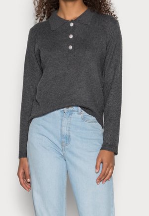 Pull en tricot gris avec un col, ornée de trois boutons décoratifs et de manches longues, assorti à un jean taille haute bleu clair.