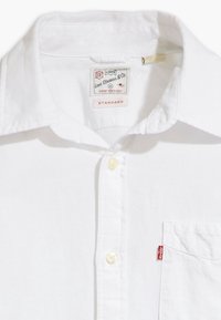 Witte button-up shirt van katoen, met een klassieke kraag, één borstzak en een rood logo-label op de zak.