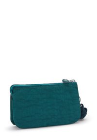 Teal ritsportemonnee van textuurstof, ronde vorm, zijkant met pompon detail en contrasterende ritsafwerking. Compact en praktisch ontwerp.