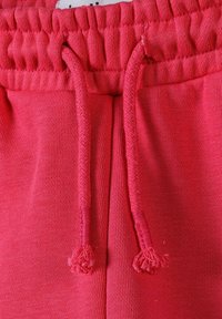 Rosa sweatpants med strukturerad tyg, elastisk midja med rynkade detaljer, och matchande dragsko med tofsar.
