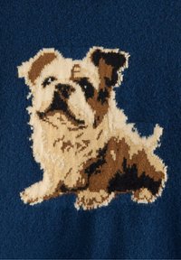 Uld tæppe med et tekstureret design af en cremefarvet og brun hund mod en mørkeblå baggrund. Detaljeret pelsmønster med tydelige ansigtstræk.