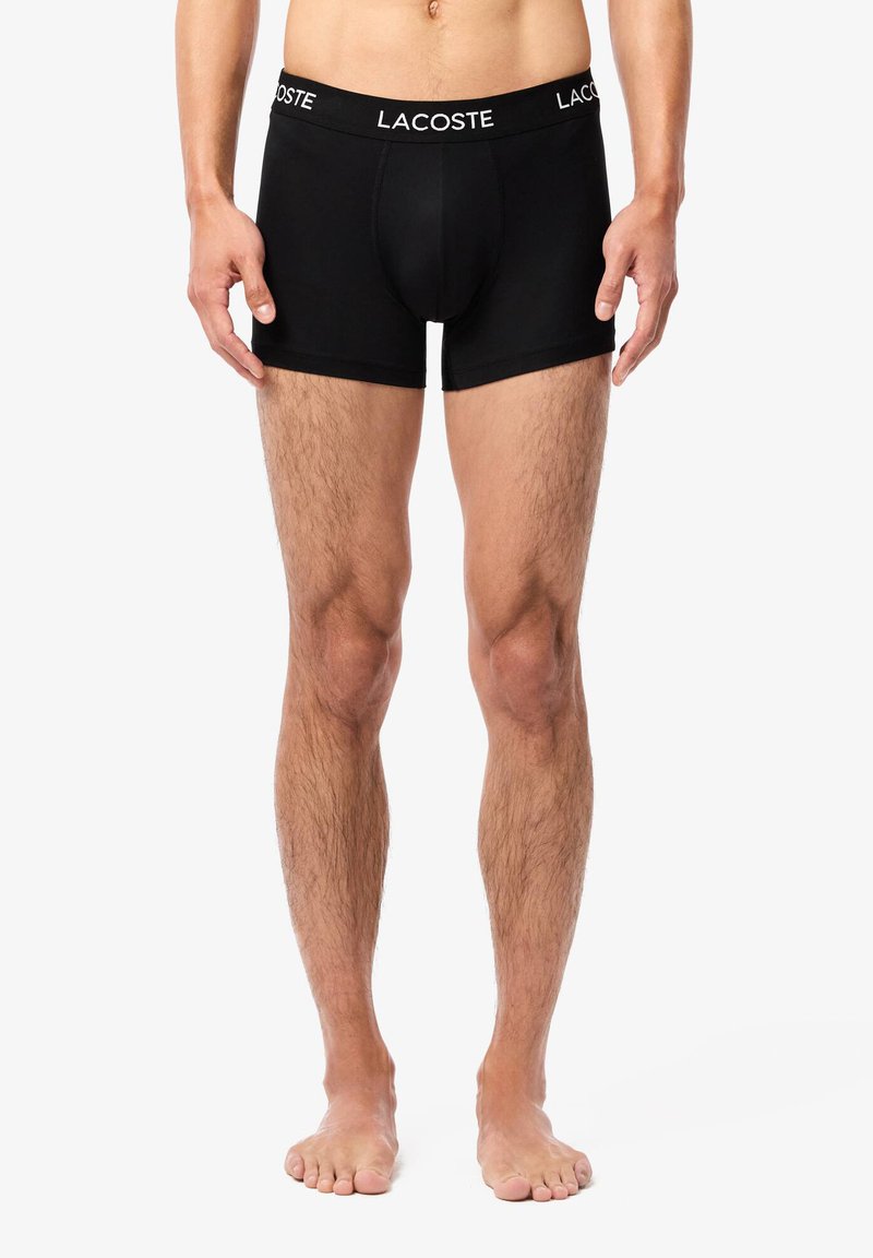 Boxer-briefs noirs en tissu doux, avec un design uni, un ajustement près du corps et une ceinture élastique avec logo.