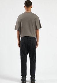 Szara koszulka z krótkim rękawem, luźny krój, zestawiona z czarnymi dżinsami. Czarne trampki z elastycznymi mankietami i subtelnymi teksturowanymi akcentami.