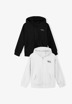 Zwei Kinder-Kapuzenjacken mit Reißverschluss, eine schwarz und eine weiß, beide mit Fronttaschen und kleinem aufgedrucktem Text auf der linken Brust.