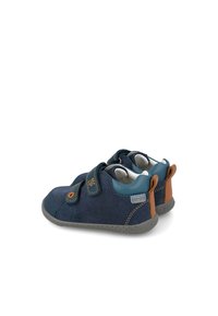 Zapatos infantiles de color azul marino, fabricados en ante, con dos correas de velcro y suelas de goma gris. Detalles en color marrón claro en el talón y costuras en color marrón claro.