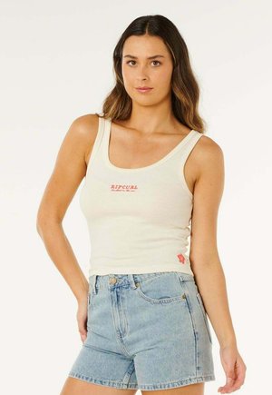 Beiges Ripcurl-Rippstrick-Top mit Rundhalsausschnitt und kleinem rotem Logo auf der Brust, kombiniert mit hellblauen Jeans-Shorts. Glatte Textur.