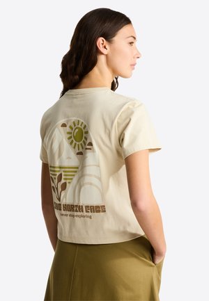 Kermanvärinen t-paita, jossa on grafiikkakuva vuorista ja auringosta. Teksti kuuluu "THE NORTH FACE" ja "never stop exploring."