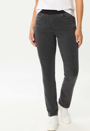 Graue Stretchpants mit einem schwarzen elastischen Bund und dekorativen Taschen. Der Stoff ist weich und hat eine glatte Textur. Kombiniert mit weißen Sneakern.