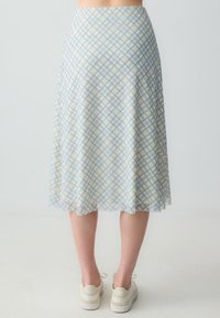 Lichtblauwe geruite midi-jurk met een vloeiende, A-lijn ontwerp. Gemaakt van een zachte, ademende stof, met overlappende vierkante patronen.