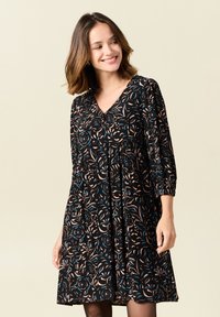 Schwarzes Kleid mit floralem Muster in Beige und Teal. Es hat einen V-Ausschnitt, dreiviertel lange Ärmel und eine lockere Passform mit Faltenbildung an der Taille.