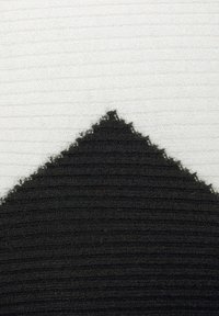 Black and white textured textile featuring a central black triangle against a white ribbed background with frayed edges.