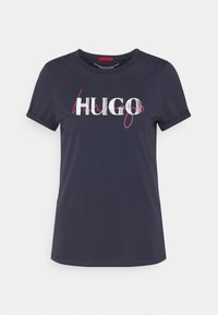 Tmavě námořnické tričko s krátkým rukávem vyrobené z měkké bavlny, s výrazným bílým a růžovým nápisem "HUGO" přes hruď. Jednoduchý design s kulatým výstřihem.