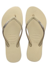 Flip-flops aurii cu sclipici, având o talpă texturată bej. Se remarcă printr-un design elegant cu curele opuse și branding embosat pe curea stângă.