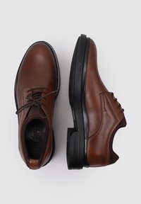 Zapatos de cuero marrón con un acabado suave, que presentan una puntera redonda, un diseño de cordones y una suela de goma negra contrastante.