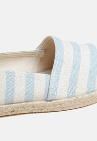 Canvas espadrille with blue and white stripes, rounded toe, and natural jute sole. Features a soft fabric upper and plain interior lining.