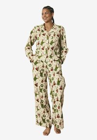 Jouluinen pyjamapaketti, jossa on vaaleanpunainen kangas, jossa on vihreitä ja punaisia juhlakuoseja, mukaan lukien seppeleet, puut ja hahmot. Olen pehmeä ja väljä malli.