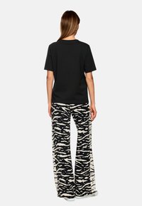 Black t-shirt with a relaxed fit, paired with black and white zebra-patterned wide-leg pants with a textured fabric.