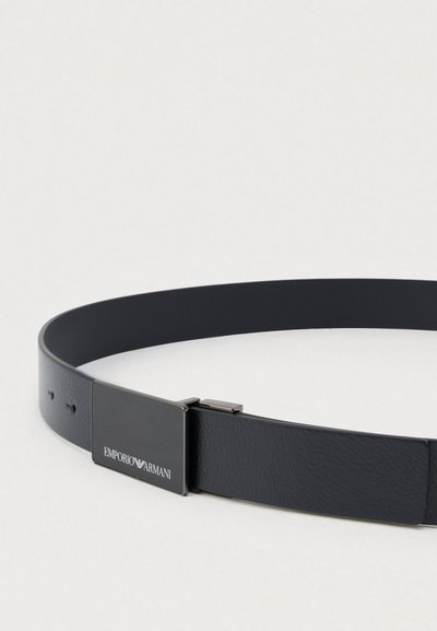 Melnas ādas josta ar gludu tekstūru, kas ir aprīkota ar sudraba toņa taisnstūrveida sprādzi un uz tās iespiestu logotipa detaļu.