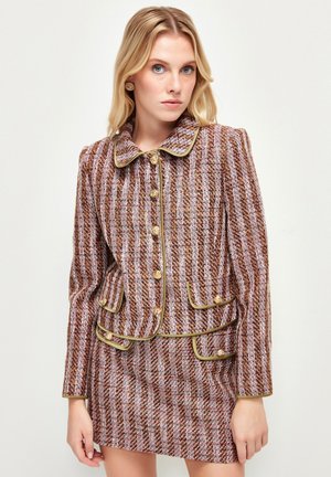 Tweed jacket and skirt set featuring a brown and cream striped pattern, gold accent trim, and decorative buttons, with a rounded collar.