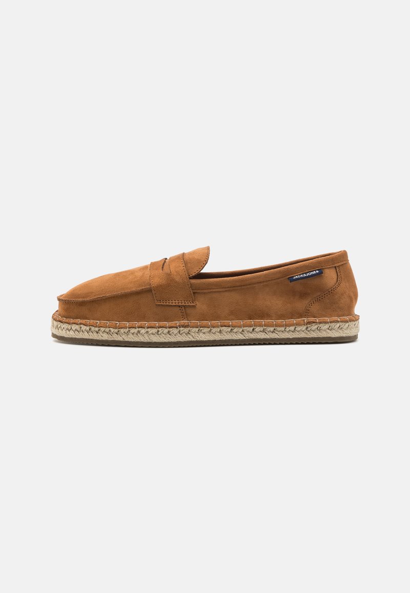 Brown suede slip-on shoe with a rounded toe, featuring a woven jute sole and a small accent strap across the front.