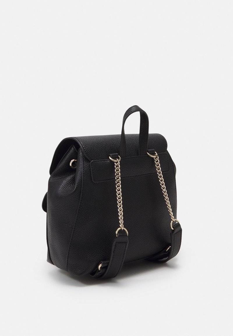 Sac à dos en cuir noir texturé avec une chaîne dorée et des bretelles en cuir, une poignée supérieure et une fermeture à rabat.