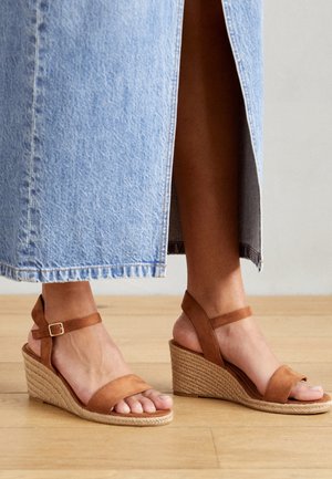 Ruske suède wedge sandale s pletenim jute potplatom, s širokom trakicom za prste i podesivom trakicom oko zapešća.