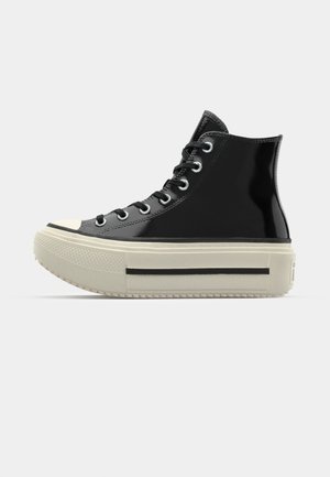 Black patent leather high-top sneaker with a cream-colored platform sole, featuring black accents and metal eyelets.