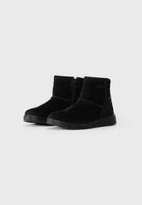 Botas de tobillo de ante negro con puntera redondeada, cierre de cremallera y suela de goma texturizada. Presenta un diseño minimalista y acentos de costura.