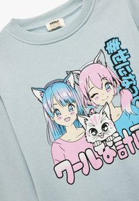 Sudadera azul claro con diseños gráficos de dos personajes con orejas de gato, cabello colorido y un gato de caricatura, con texto en japonés.