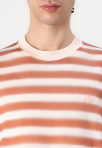 Stripped cotton T-shirt featuring horizontal orange and white stripes, a round neckline, and a small embroidered logo on the chest.