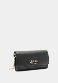 Portafoglio nero in pelle con finitura texture, accessori in oro e dettaglio a catena. Presenta una chiusura a patta e un logo brand impresso.