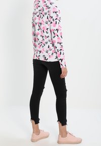 Felpa con cappuccio dal motivo floreale rosa su sfondo grigio; abbinata a jeans skinny neri strappati e sneakers rosa.