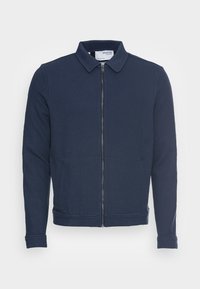 Merijapari vetoketjullinen takki, joka on valmistettu teksturoidusta kankaasta. Takissa on kauluspääntie, sivutaskut sekä ribattu hihansuu ja helma.