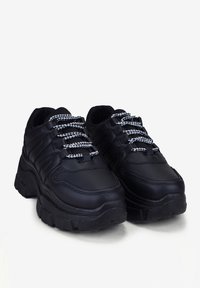 Sneakers chunky neri realizzati in materiale sintetico con una finitura texturizzata. Presentano lacci a scacchi bianchi e neri e una suola spessa.