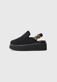 Čierne platformové sandále so slingback dizajnom, jemným semišovým vrchom, hrubou gumovou podrážkou a zlatým detailom vo forme srdca na remienku.