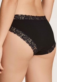 Schwarze Baumwoll-Bikiniunterwäsche mit einer Spitzeneinfassung entlang des Taillenbundes und der Beinöffnungen, die einen zarten Designkontrast zum einfarbigen Stoff bietet.