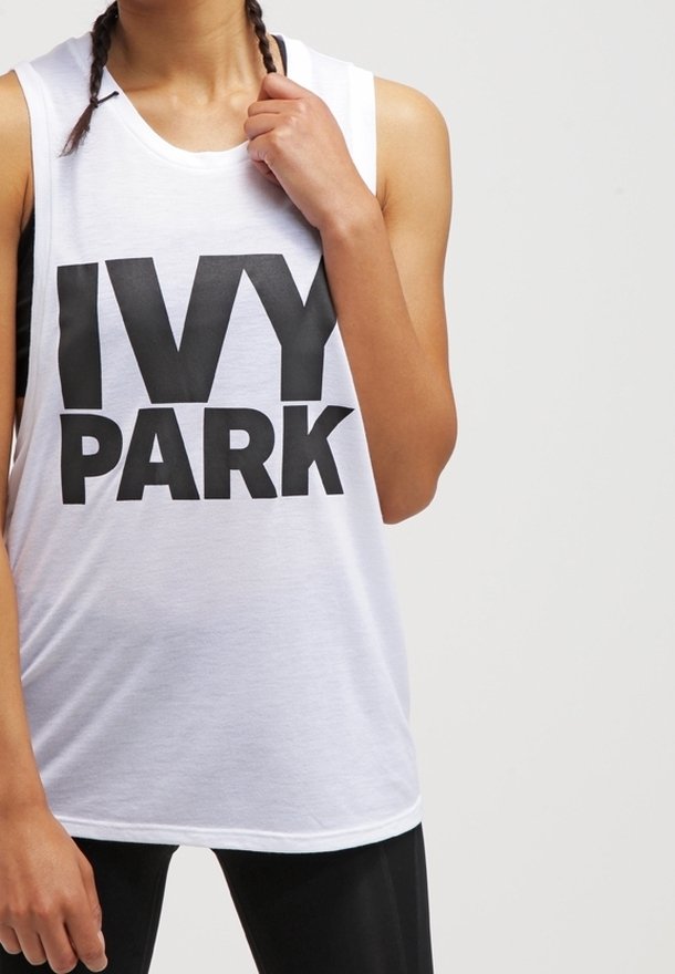 Hvid ærmeløs tanktop med fed sort 'IVY PARK' tekst, lavet af blødt stof, med en afslappet pasform og rund halsudskæring.